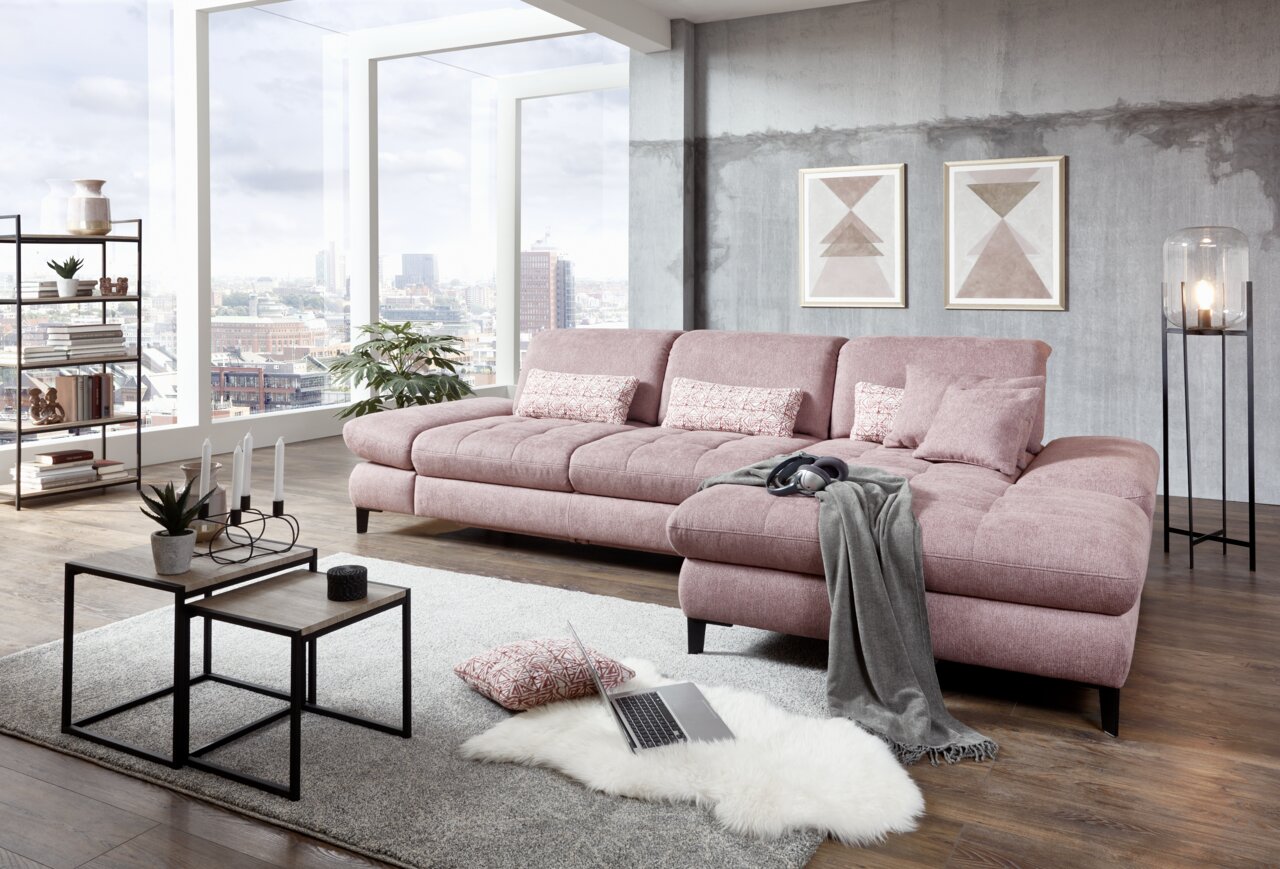 Moderne rosa Rundecke in einem stilvollen Wohnzimmer mit großen Fenstern, die einen Blick auf die Stadt bieten. Perspektive von vorne rechts.