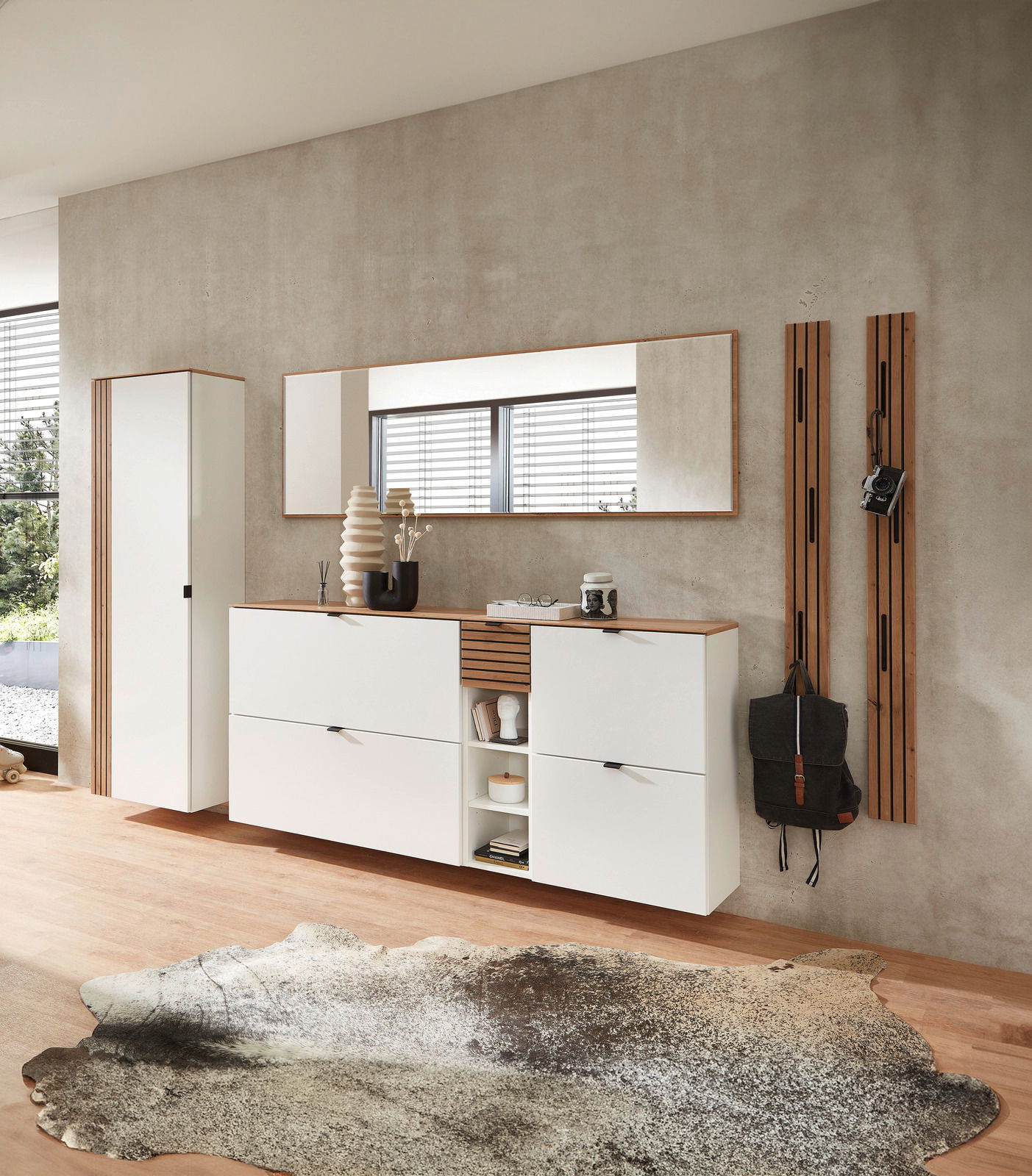 Moderne Garderobeneinrichtung in Weiß mit hängendem Schuhschrank, Spiegel und Garderobenpaneel, seitliche Perspektive.