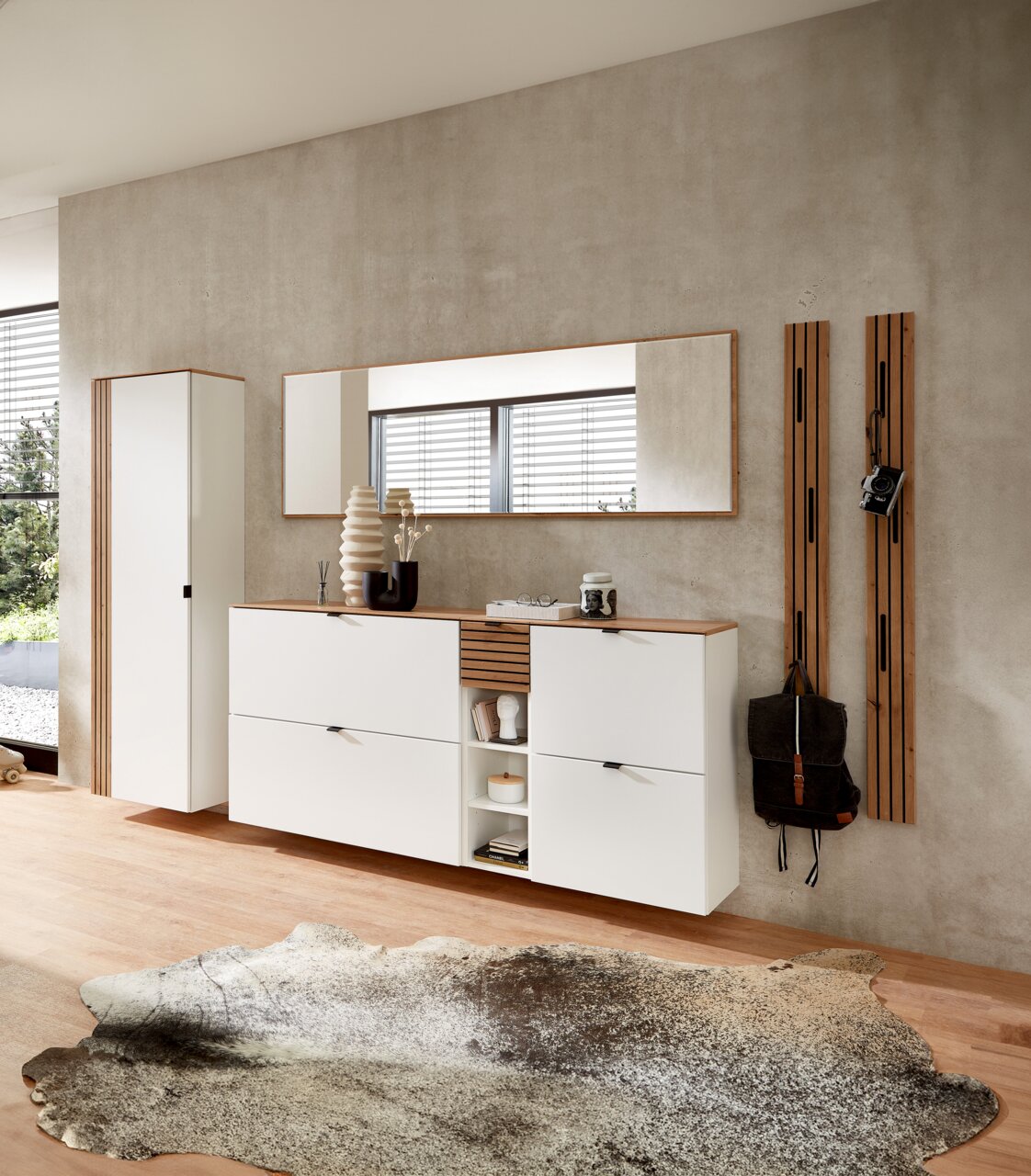 Moderne Garderobeneinrichtung in Weiß mit hängendem Schuhschrank, Spiegel und Garderobenpaneel, seitliche Perspektive.