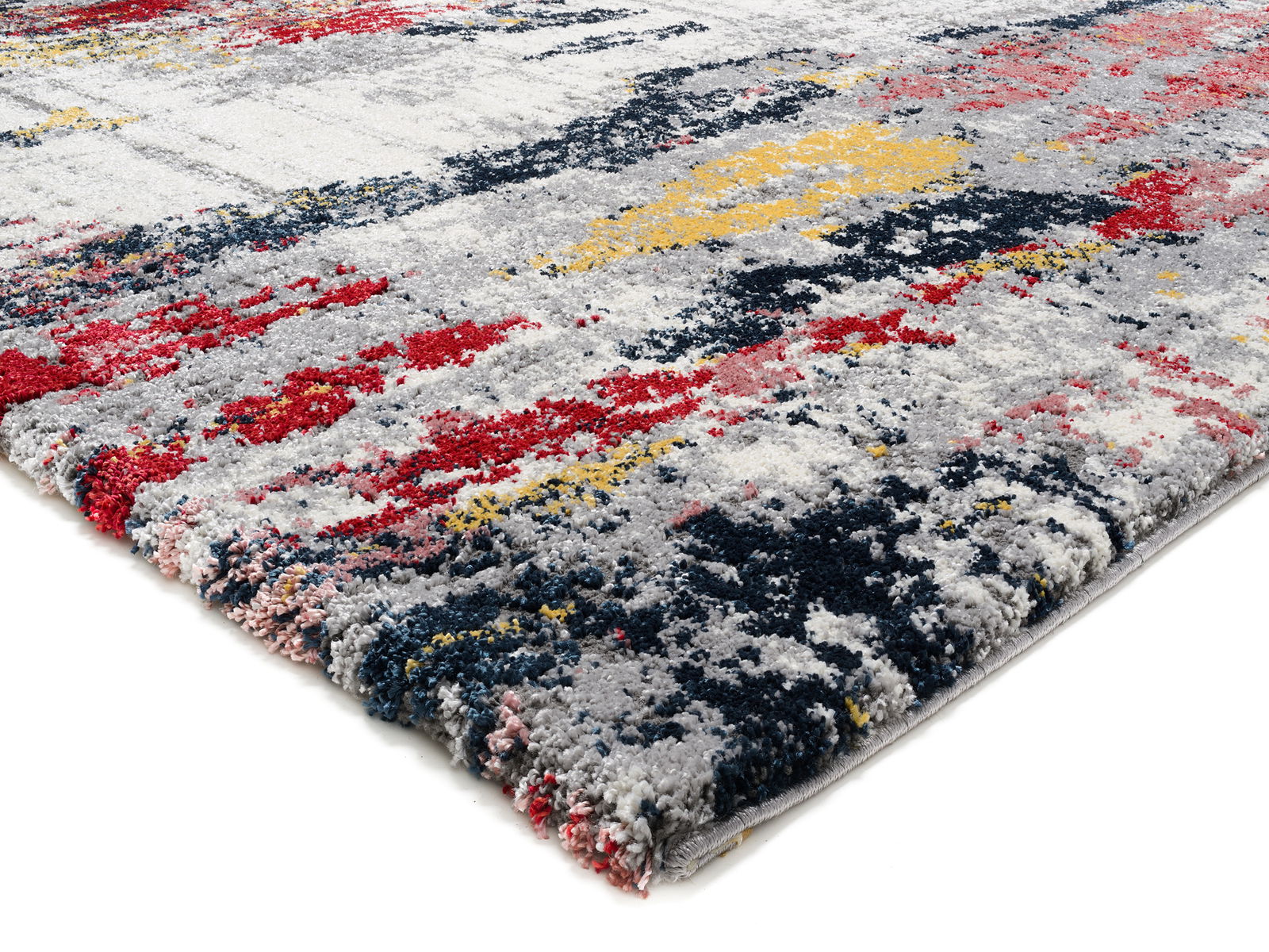 Nahaufnahme eines Designer Teppichs mit abstraktem Muster in Rot, Gelb, Blau und Grau aus seitlicher Perspektive.