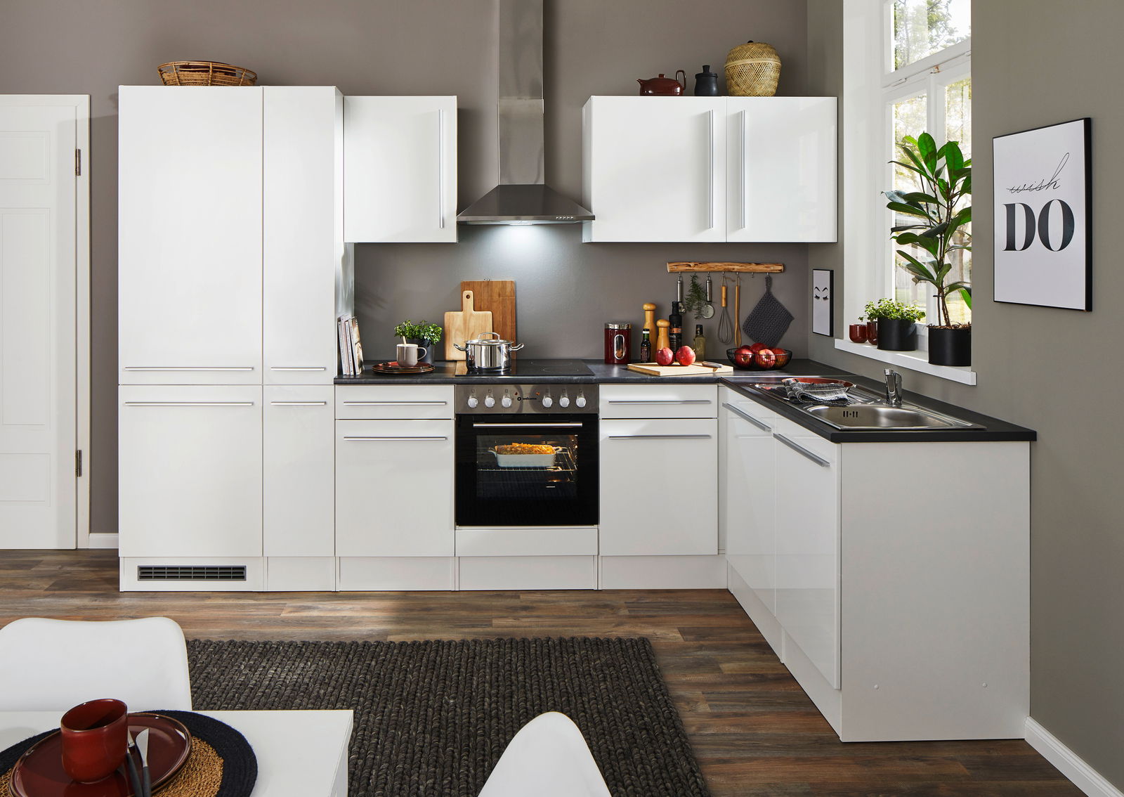 Moderne weiße Küche mit Eckunterschrank, Herd und Spüle, aus der Perspektive des Essbereichs fotografiert.