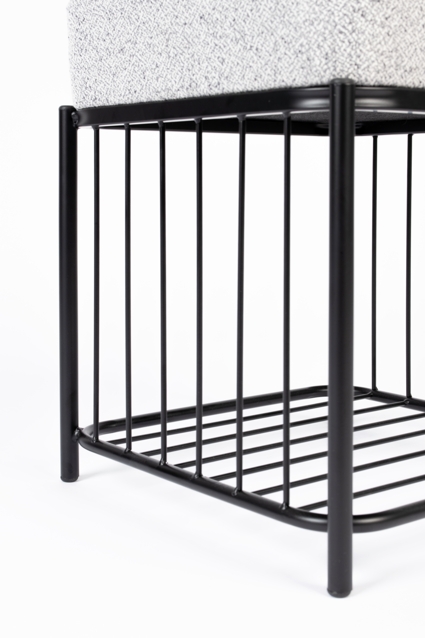 Nahaufnahme eines Hockers mit schwarzem Metallgestell und gepolsterter Sitzfläche, seitliche Perspektive.