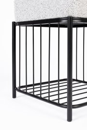 Nahaufnahme eines Hockers mit schwarzem Metallgestell und gepolsterter Sitzfläche, seitliche Perspektive.