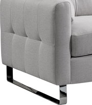 Detailaufnahme eines hellgrauen, gepolsterten Stoffsofas mit gesteppter Seitenpartie und glänzendem Metallkufenfuß, seitliche Perspektive