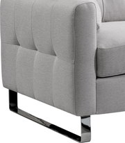Detailaufnahme eines hellgrauen, gepolsterten Stoffsofas mit gesteppter Seitenpartie und glänzendem Metallkufenfuß, seitliche Perspektive