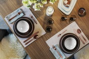 Elegante 30-delige bestekset Cortina in koper, van bovenaf gefotografeerd op een stijlvol gedekte tafel, met bruine borden en witte schalen.