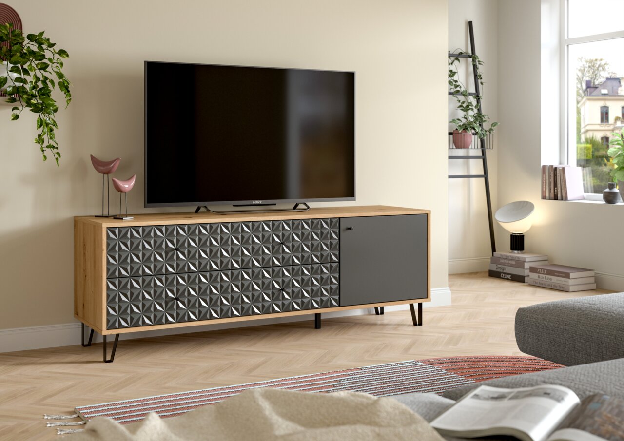 MID.YOU TV-Lowboard PRISMA Modernes TV-Lowboard aus hellem Holz mit geometrisch gemusterter Front und grauer Tür auf schwarzen Metallfüßen, im Wohnzimmer mit Fernseher darauf, Perspektive: frontale leicht schräge Ansicht von links.