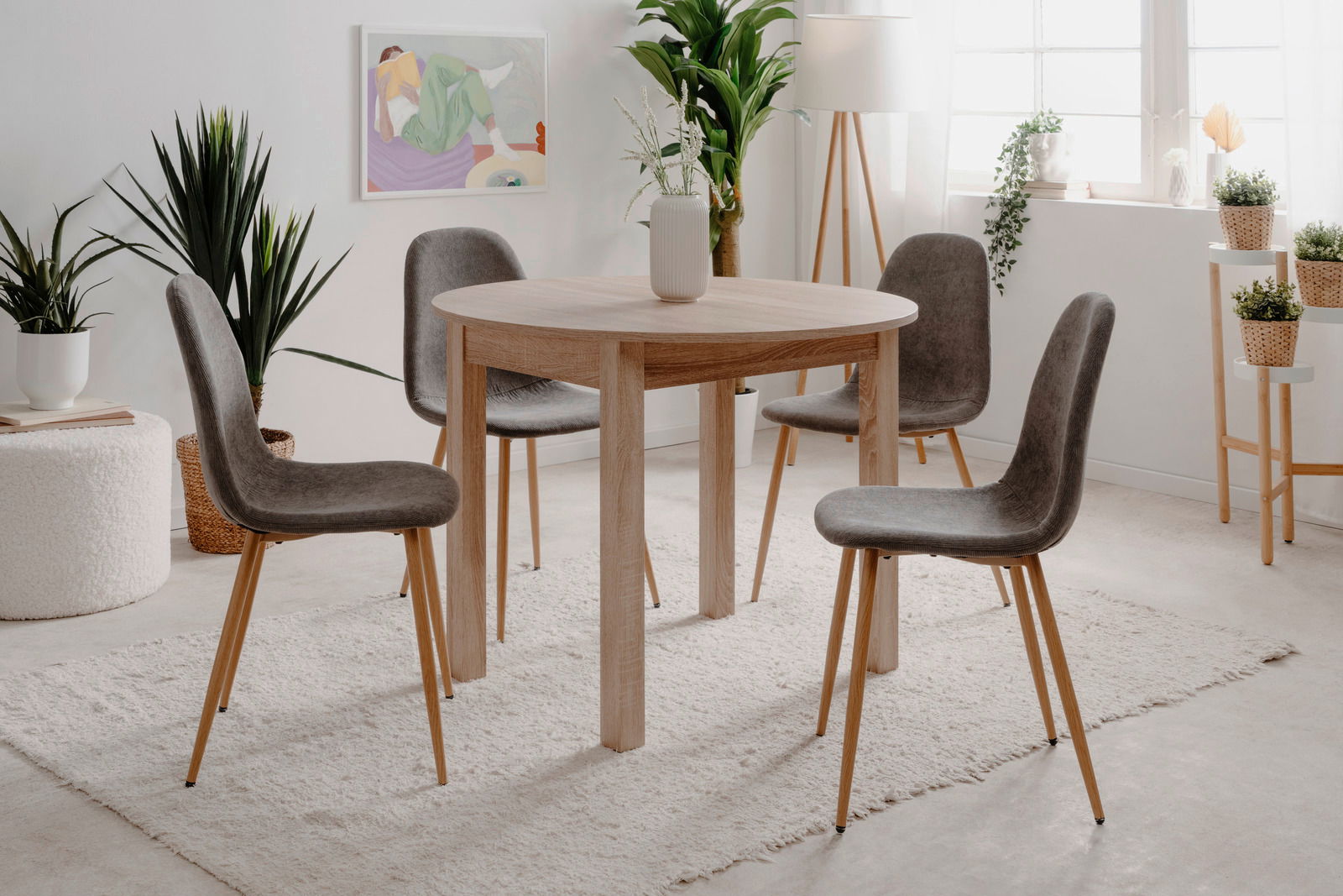 Runder Esstisch aus Holz mit vier grauen Stühlen in einem hellen, modernen Raum, seitliche Perspektive