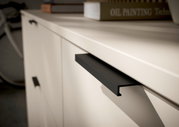 Close-up van een tv-lowboard met moderne zwarte handgrepen en een glad, licht oppervlak.