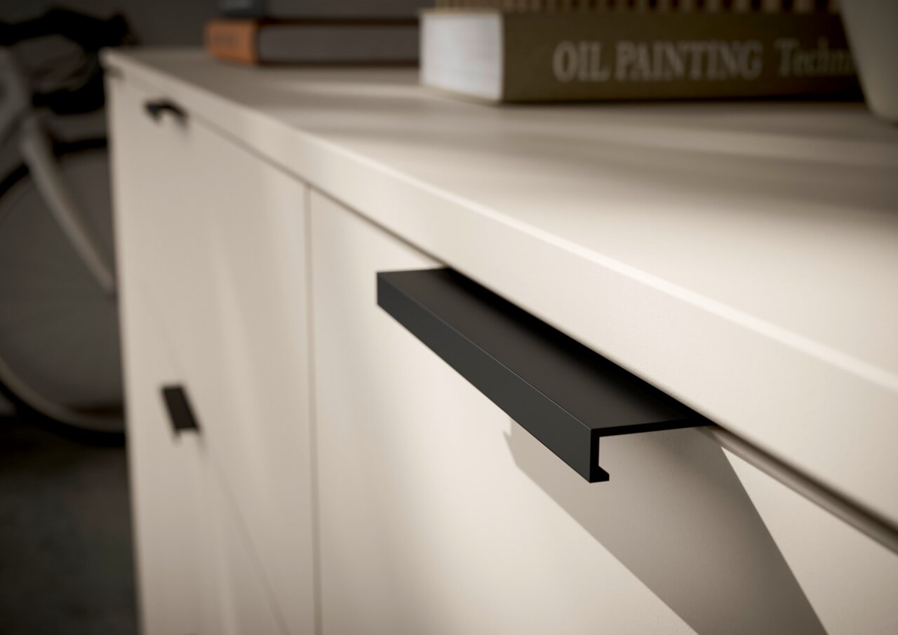 Close-up van een tv-lowboard met moderne zwarte handgrepen en een glad, licht oppervlak.
