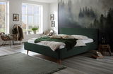 Modernes Polsterbettgestell in einem stilvoll eingerichteten Schlafzimmer mit Waldblick, aus der Seitenperspektive fotografiert.