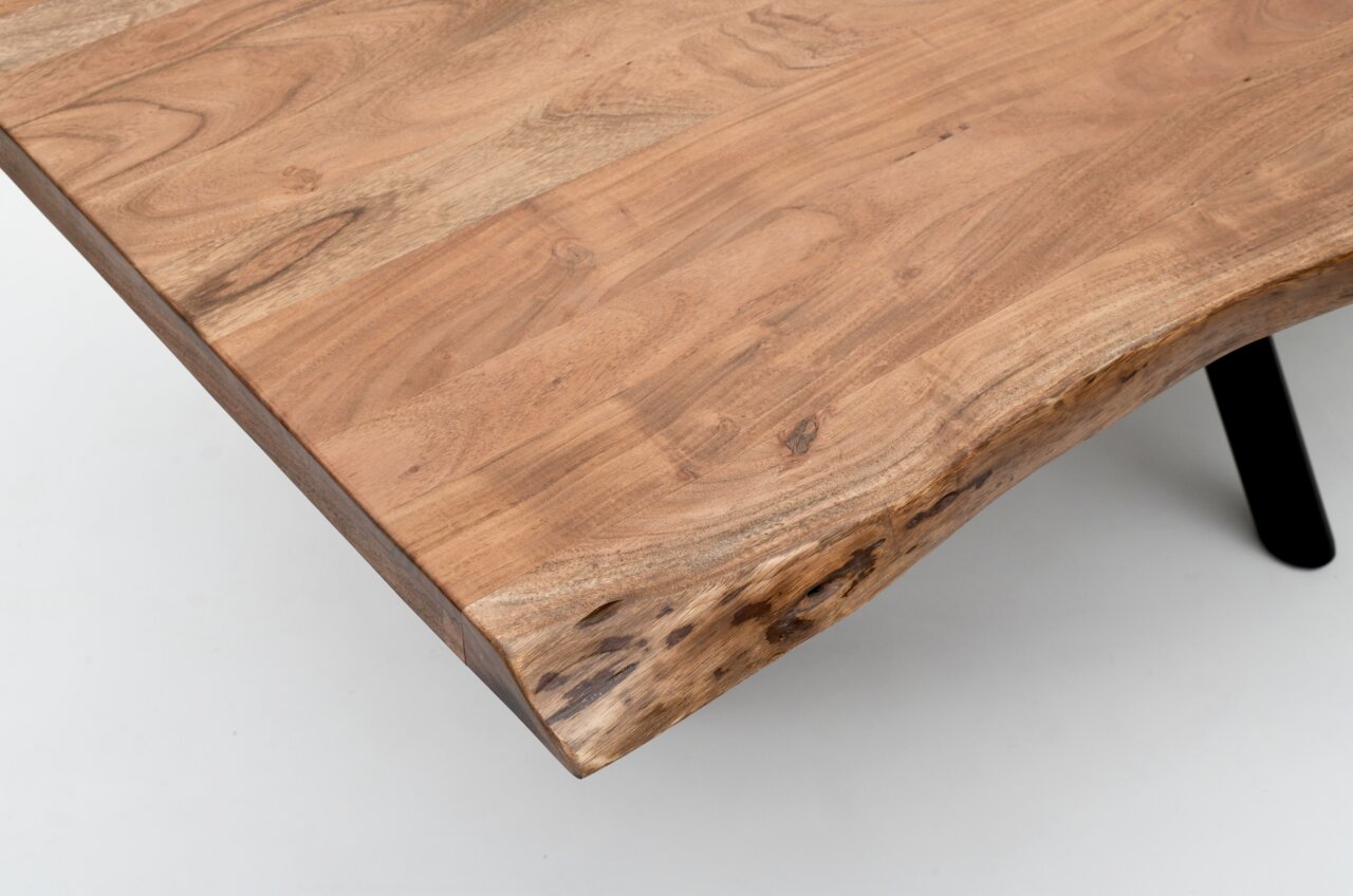 Nahaufnahme eines Esstisches aus Holz mit natürlicher Kante, von oben betrachtet.