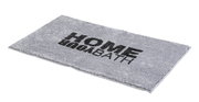 Grauer rechteckiger Badteppich mit der Aufschrift 'HOME BATH' in schwarzer Schrift, perspektivisch von der Seite fotografiert.