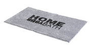 Grijs rechthoekig badmatje met het opschrift 'HOME BATH' in zwarte letters, in perspectief vanaf de zijkant gefotografeerd.