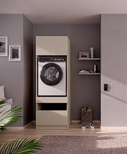 Frontaanzicht op een moderne witte wasmachine met zwarte deur, ingebouwd in een beige wasmachinekast met opbergruimte, in een strak ingerichte grijze kamer met wandplanken.