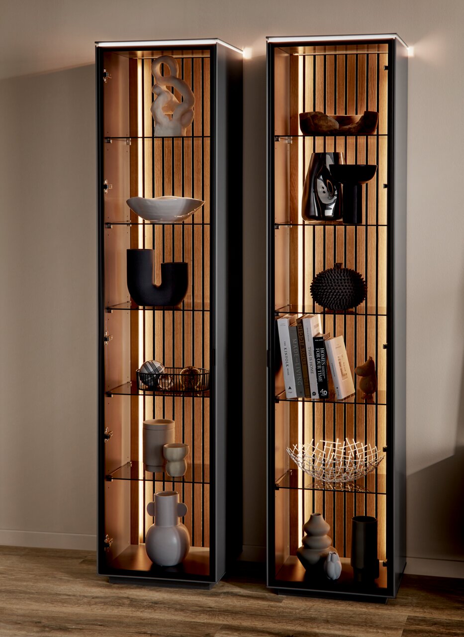 Twee moderne vitrinekasten met glazen planken en decoratieve voorwerpen, gezien vanaf de voorkant, met ingebouwde verlichting.