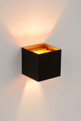 Moderne schwarze Wandleuchte IO in Würfelform mit warmem Licht, seitliche Perspektive