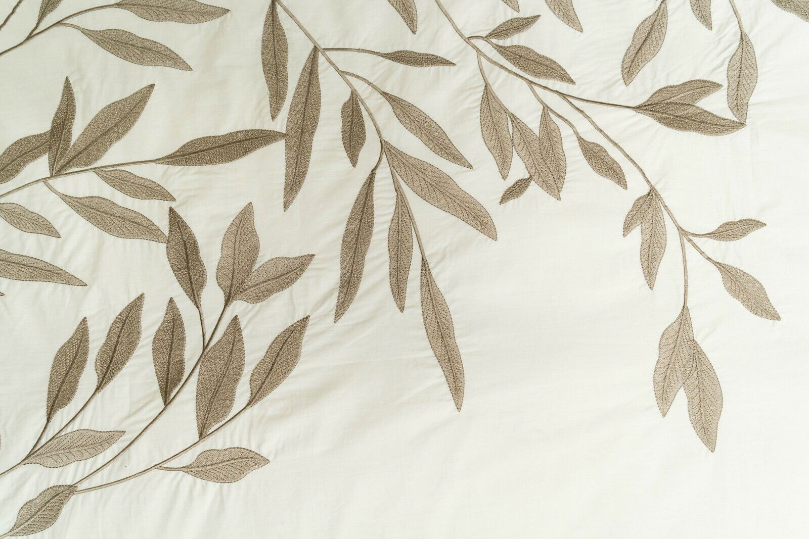 Nahaufnahme einer Bettwäsche mit einem eleganten Blattmuster in natürlichen Tönen.