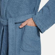Nahaufnahme eines blauen Bademantels mit Schalkragen in Größe L, zeigt eine Hand in der Tasche und den Gürtel um die Taille.