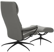 Seitliche Ansicht eines grauen Einzelsessels mit passendem Hocker, beide mit schwarzem Drehfuß.