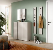 Modernes Garderoben-Set im Flur mit weißem Schuhschrank, rechteckigem Wandspiegel und zwei schlanken Wandgarderobenpaneelen mit Haken, perspektivisch in leichter Schrägansicht von vorne.