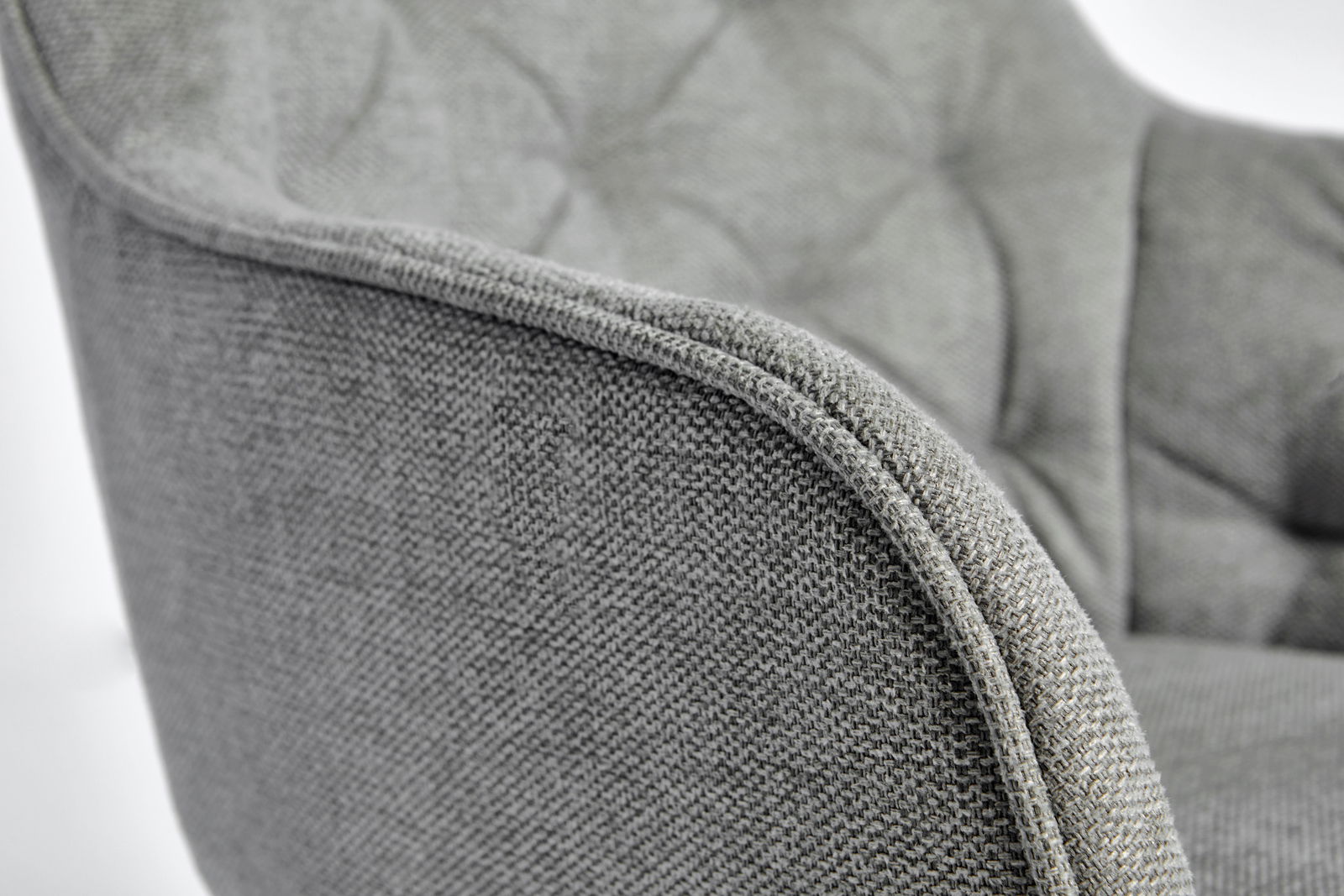 Nahaufnahme eines grauen Stuhls mit texturierter Stoffoberfläche, seitliche Perspektive.
