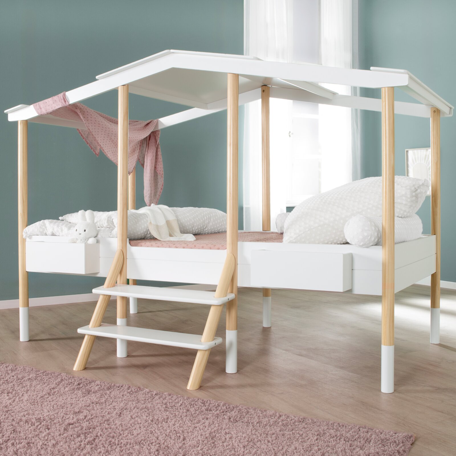 Hausbett für Kinder in Weiß und Naturholz mit Dachrahmen, zwei Schubladen und passender zweistufiger Leiter, aus schräger Frontansicht