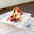 Rechteckiger Brotteller mit Dessert aus Sahne, Beeren und Keksstücken, von oben fotografiert.