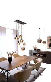 Moderne Hängeleuchte mit mehreren Glaskugeln, von der Decke hängend über einem Esstisch, seitliche Perspektive.