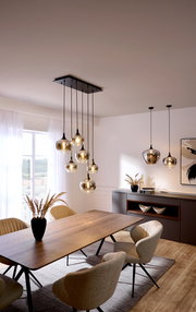 Moderne Hängeleuchte mit mehreren Glaskugeln, von der Decke hängend über einem Esstisch, seitliche Perspektive.