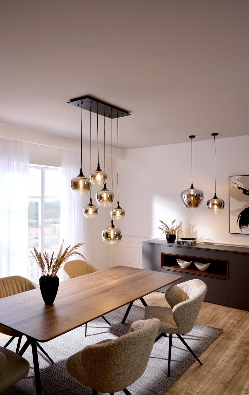 Moderne Hängeleuchte mit mehreren Glaskugeln, von der Decke hängend über einem Esstisch, seitliche Perspektive.