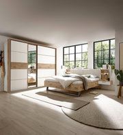 Modernes Schlafzimmer mit Schwebetürenschrank und Bettanlage in heller, natürlicher Holzoptik, seitliche Perspektive
