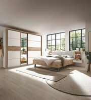 Modernes Schlafzimmer mit Schwebetürenschrank und Bettanlage in heller, natürlicher Holzoptik, seitliche Perspektive