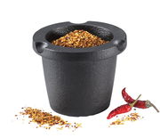 Schwarze Gewürzreibe mit Vorratsfach, gefüllt mit Chiliflocken, aus der Vorderansicht fotografiert.