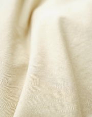 Nahaufnahme einer cremefarbenen Bettwäsche mit dezentem Fischgrätenmuster