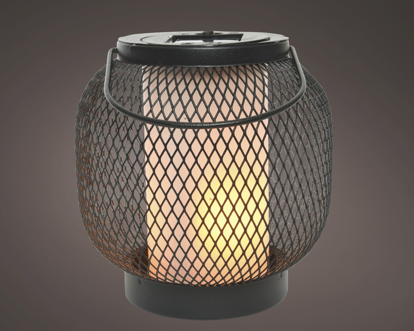 Zwarte metalen zonne-lantaarn met roosterpatroon, straalt een warm licht uit, zijaanzicht