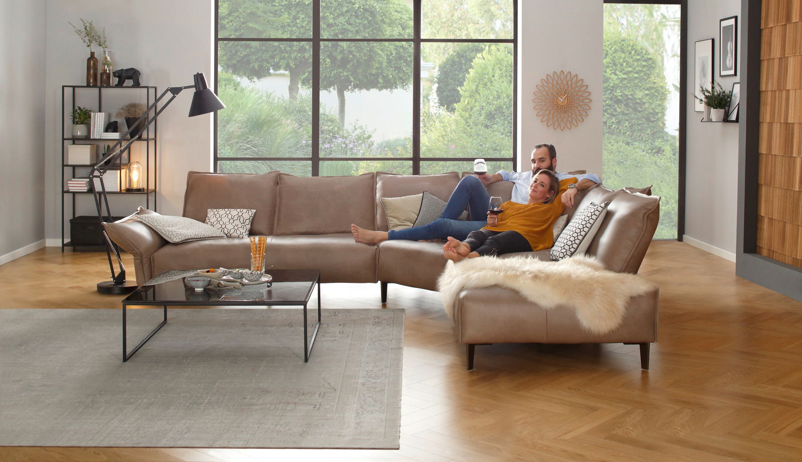 Gemütliche Polsterrundecke in einem modernen Wohnzimmer, seitliche Perspektive, mit einem Paar, das entspannt darauf sitzt.