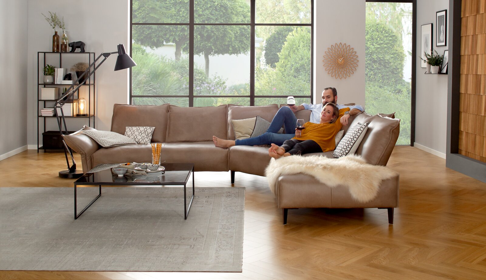 Gemütliche Polsterrundecke in einem modernen Wohnzimmer, seitliche Perspektive, mit einem Paar, das entspannt darauf sitzt.