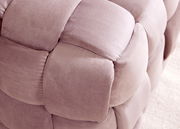 Nahaufnahme eines gepolsterten Hockers mit weichem, rosa Stoff in geflochtener Optik.