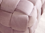 Close-up van een gestoffeerde kruk met zachte, roze stof met een gevlochten look.