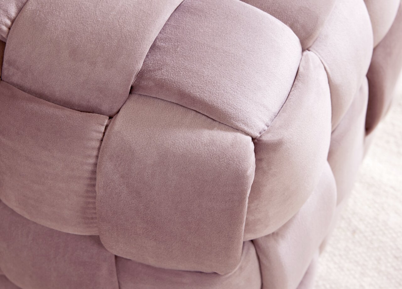 Close-up van een gestoffeerde kruk met zachte, roze stof met een gevlochten look.