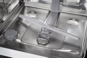 Close-up bovenaanzicht van de binnenkant van een roestvrijstalen vaatwasser met sproeiarm, filter en zoutreservoirdop