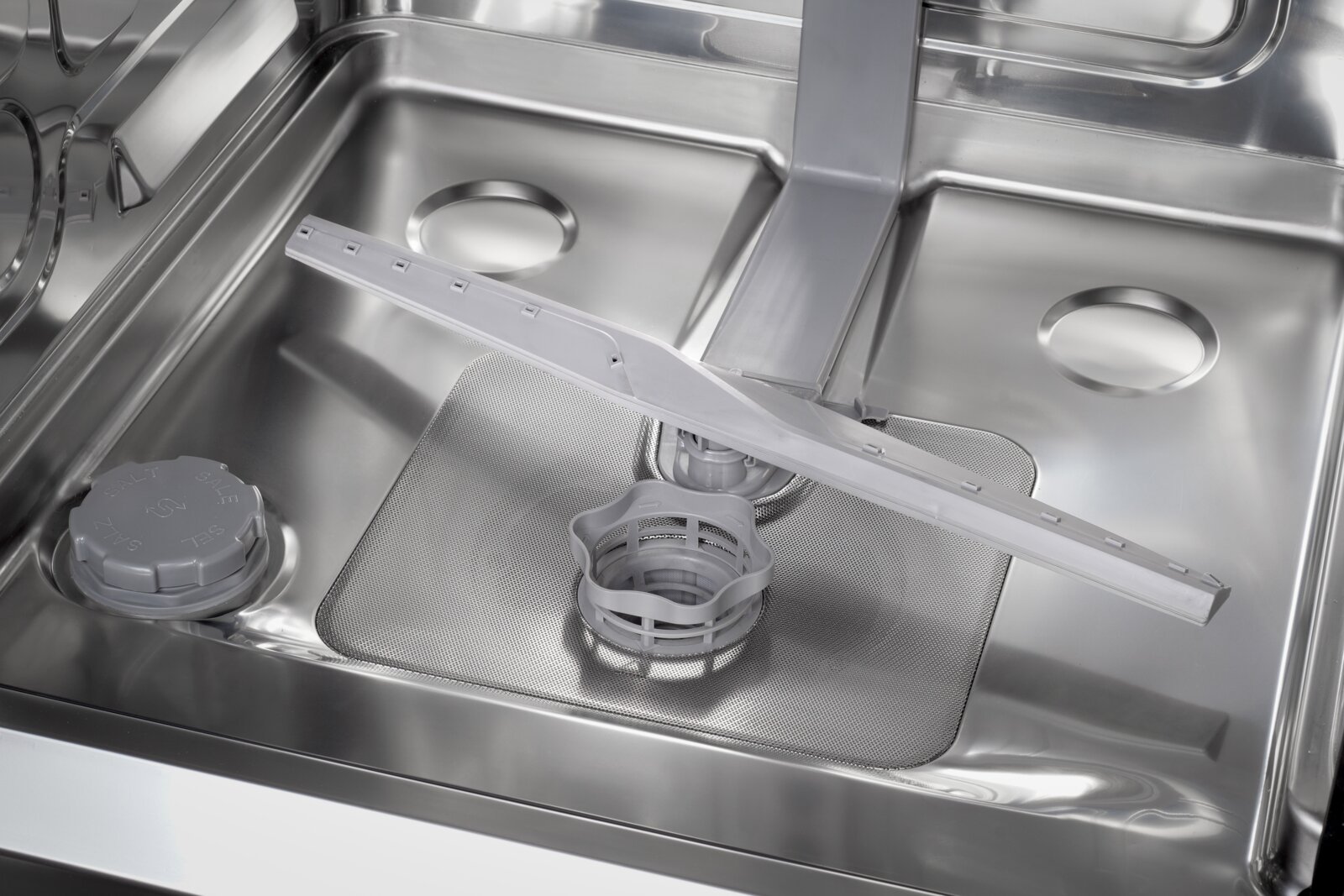 Close-up bovenaanzicht van de binnenkant van een roestvrijstalen vaatwasser met sproeiarm, filter en zoutreservoirdop