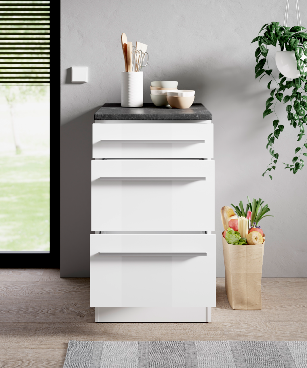 Moderner weißer Unterschrank mit vier Schubladen, von vorne betrachtet, dekoriert mit Küchenutensilien und Schalen auf der Arbeitsplatte, neben einer Papiertüte mit frischen Lebensmitteln.