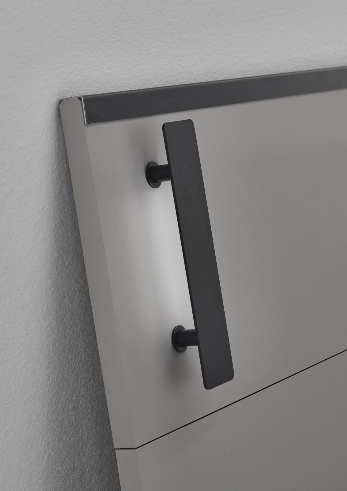 Close-up van een modern hoofdeinde van een futonbed met zwarte handgreep, gezien vanaf de zijkant