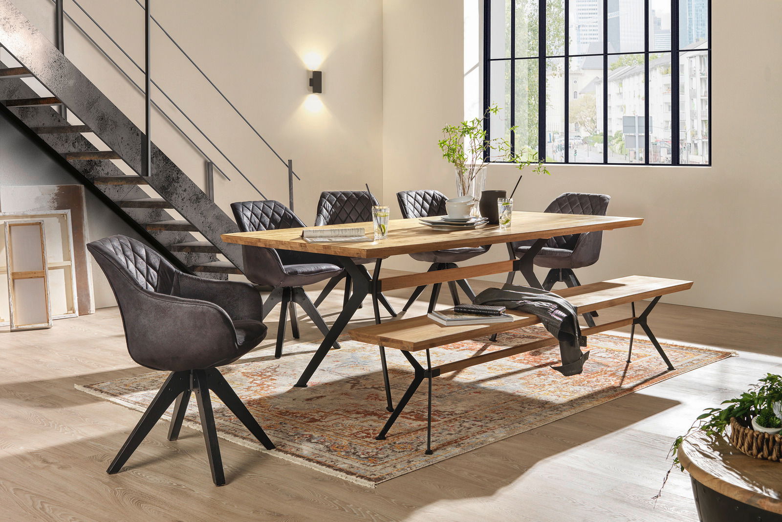 Esszimmer mit modernem Esstisch aus Holz und Metall, umgeben von gepolsterten Stühlen und einer Sitzbank, seitliche Perspektive.