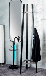 Schwarzer Standspiegel im Metallrahmen neben einer Leiter-Garderobe mit aufgehängtem Mantel, frontale Perspektive