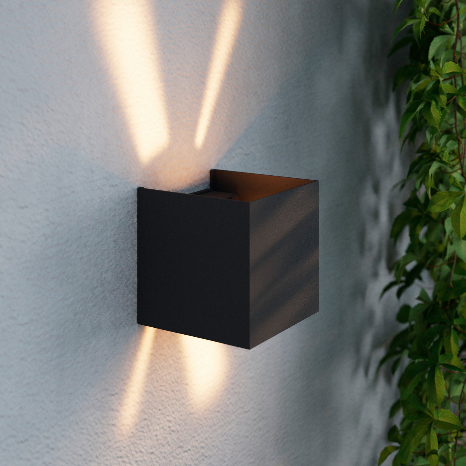 Moderne LED-Wandleuchte in schwarzem Gehäuse, die warmes Licht nach oben und unten an eine Wand abstrahlt, seitliche Perspektive.