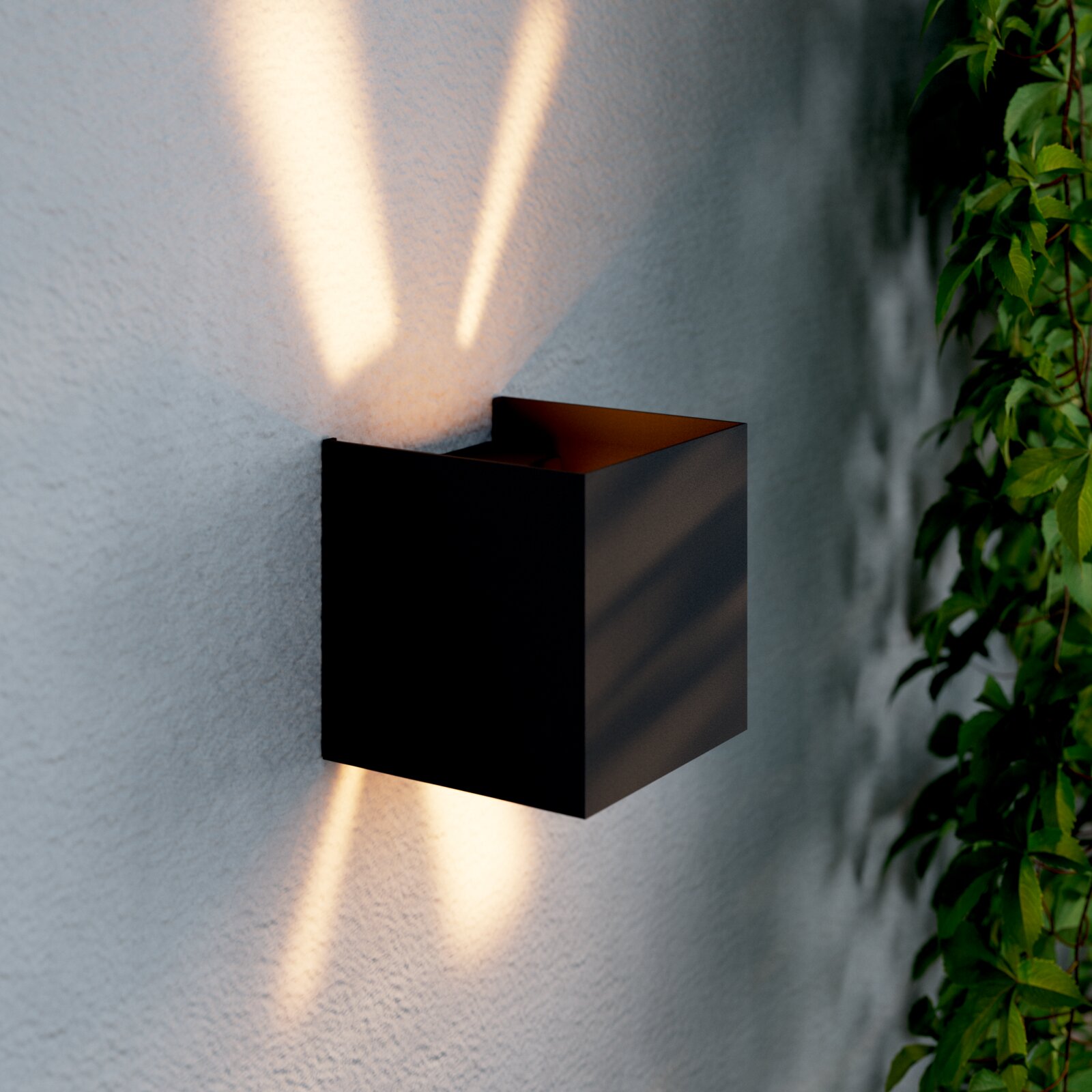 Moderne LED-Wandleuchte in schwarzem Gehäuse, die warmes Licht nach oben und unten an eine Wand abstrahlt, seitliche Perspektive.
