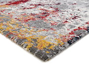 Designer Teppich mit abstraktem Muster in Grau, Rot und Gelb, aus seitlicher Perspektive fotografiert.